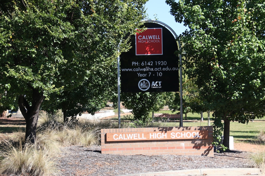 A sign reading 'Calwell high school' outside a brick wall 