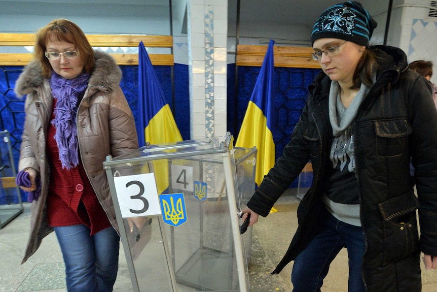 Members of a district electoral commission carry a ballot box