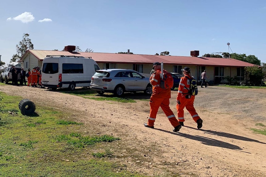 Police and SES members in orange stand next to vehicles