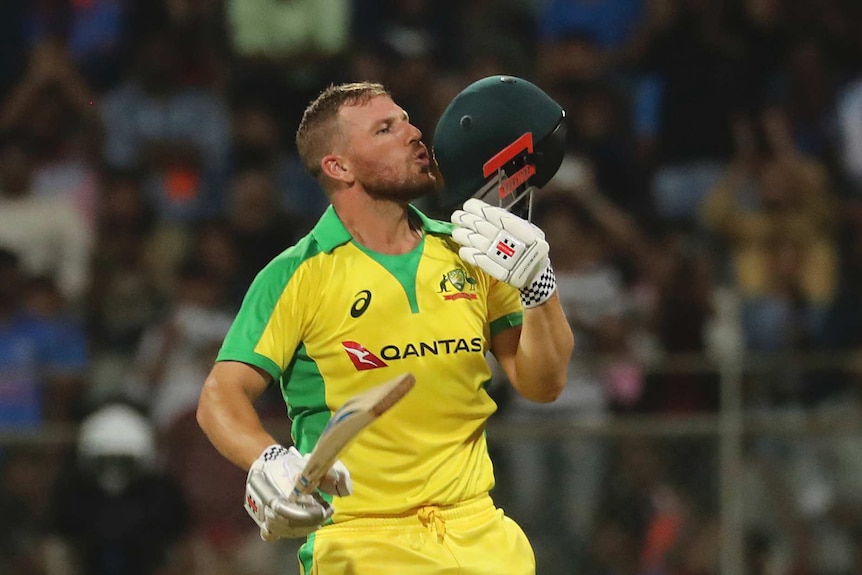 Aaron Finch kisses the badge on the front of his helmet