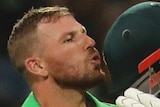 Aaron Finch kisses the badge on the front of his helmet