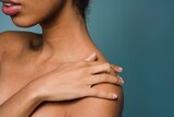 Close-up of woman touching her shoulder, in a story about women who have difficulty reaching orgasm and the causes.