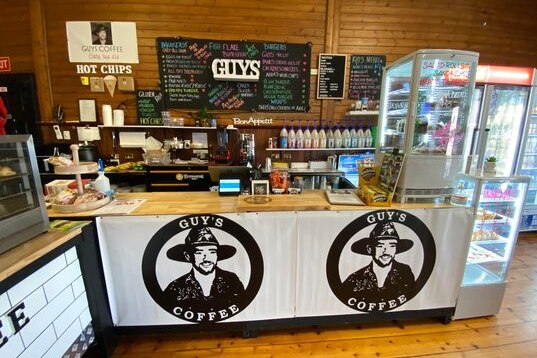 A cafe counter. A man's face and the words "Guy's Coffee" can be seen in three separate spots.