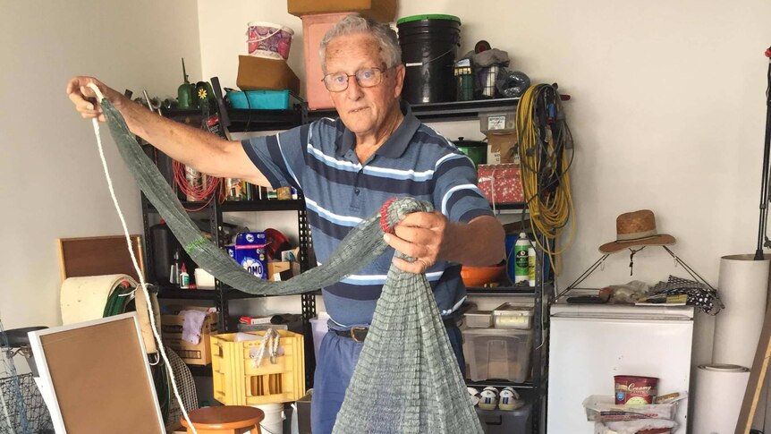 Man holding up a cast net he made from scratch