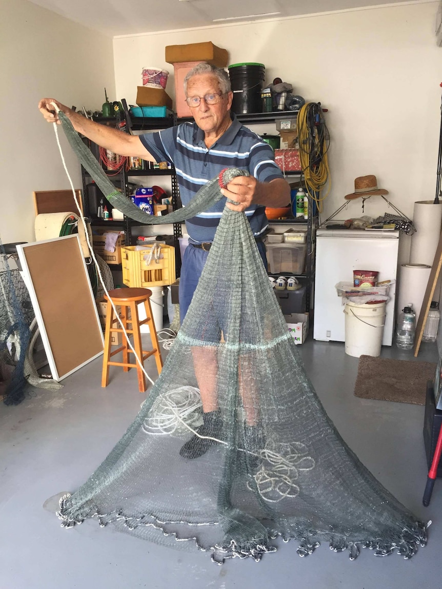 Man holding up a cast net he made from scratch
