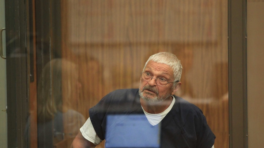 Nick Philippoussis sits behind a glass screen in court.