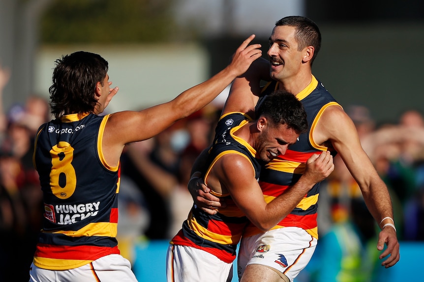 Crows players run to hug Taylor Walker who is smiling
