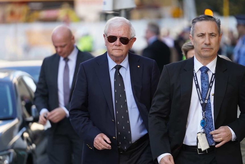 Men in suits walk along a footpath.