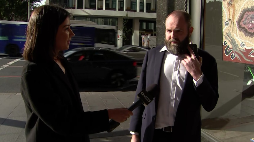 A man with a beard being interviewed outside court