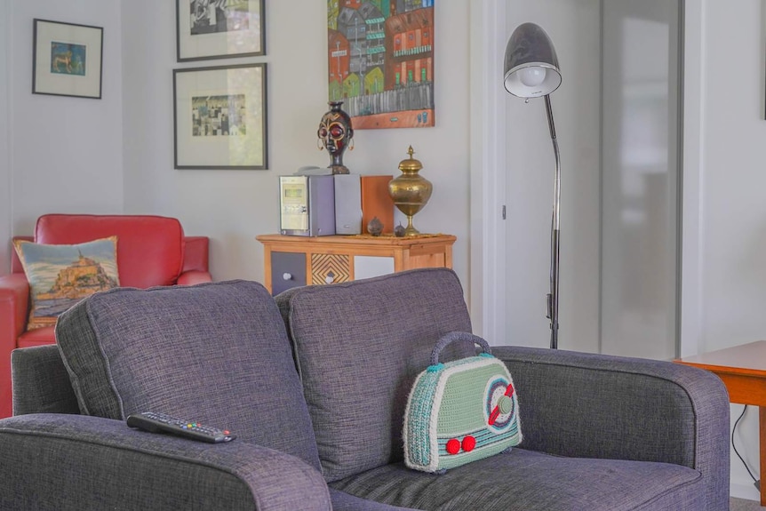 A crocheted radio sits on a couch in a colourfully decorated living room.