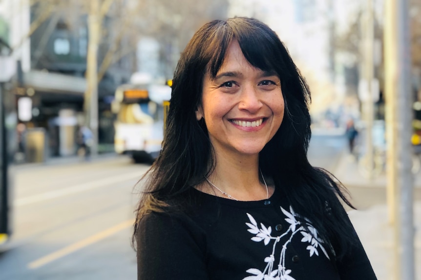 A woman smiling on a city street. 