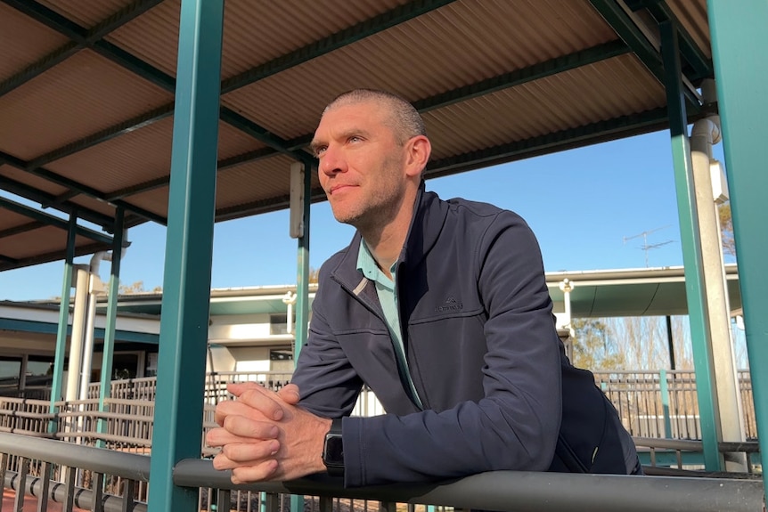 a man leaning on a frame looking out