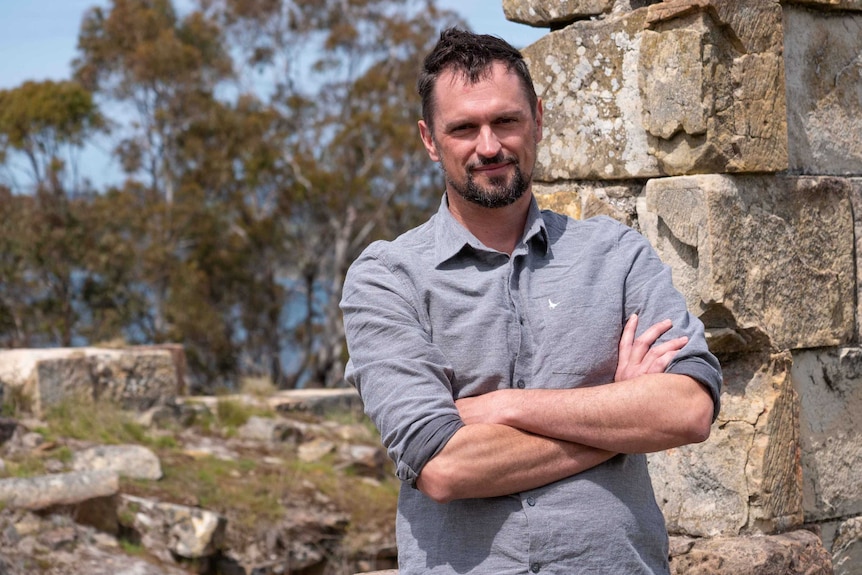 Picture of a man standing in front of an old sandstone building