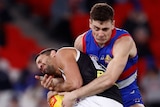 A Western Bulldogs AFL players tackles a St Kilda opponent.
