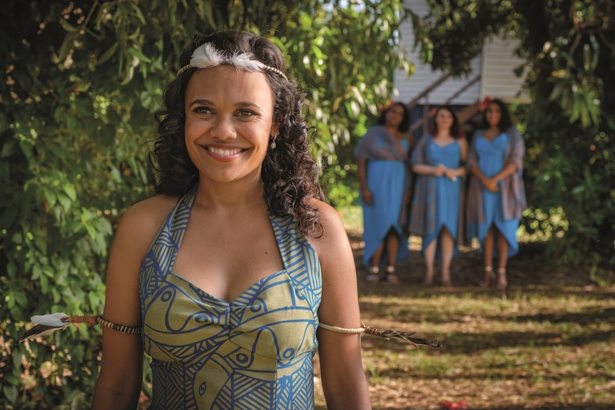 Miranda Tapsell smiles as she wears a colourful wedding dress.