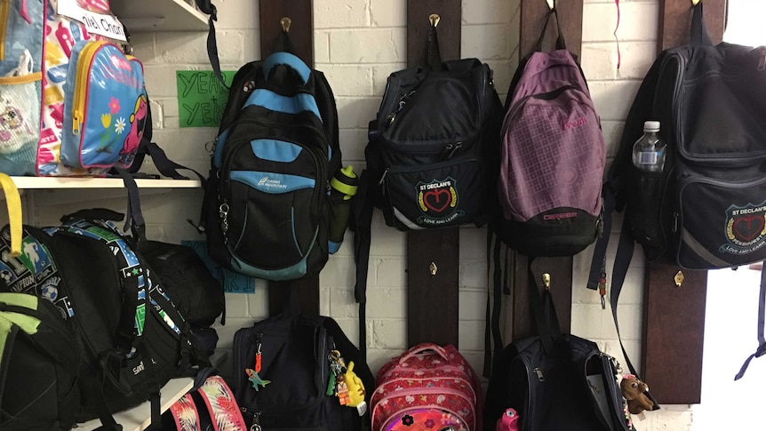 A wall of backpacks on their hooks in a classroom