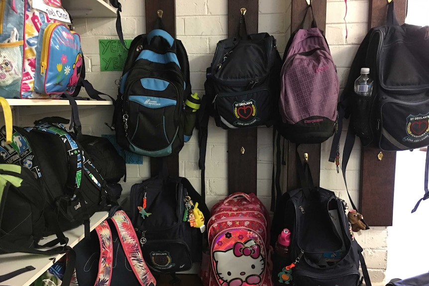 A wall of backpacks on their hooks in a classroom