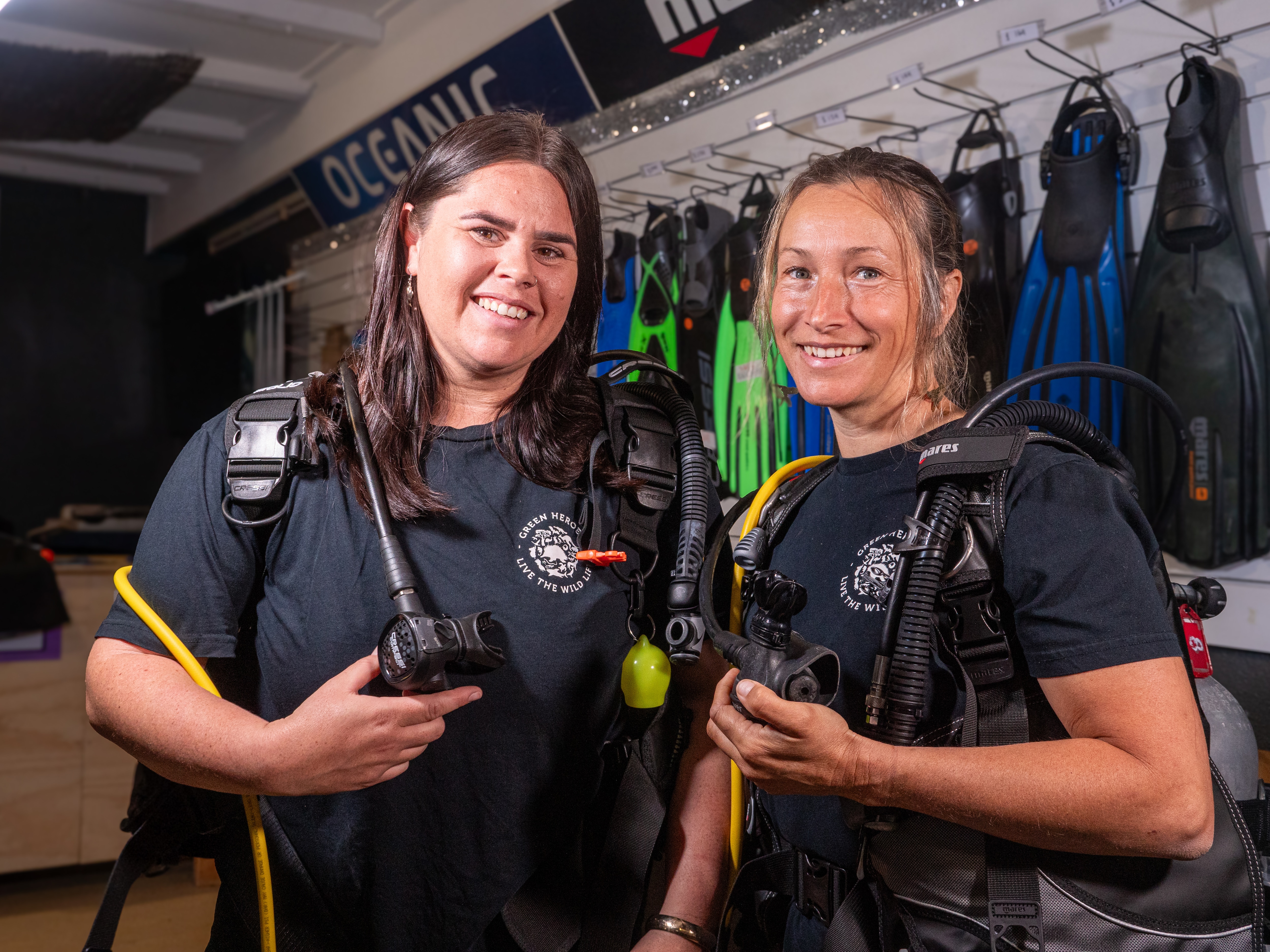 Two women in scuba gear smiling at the camera
