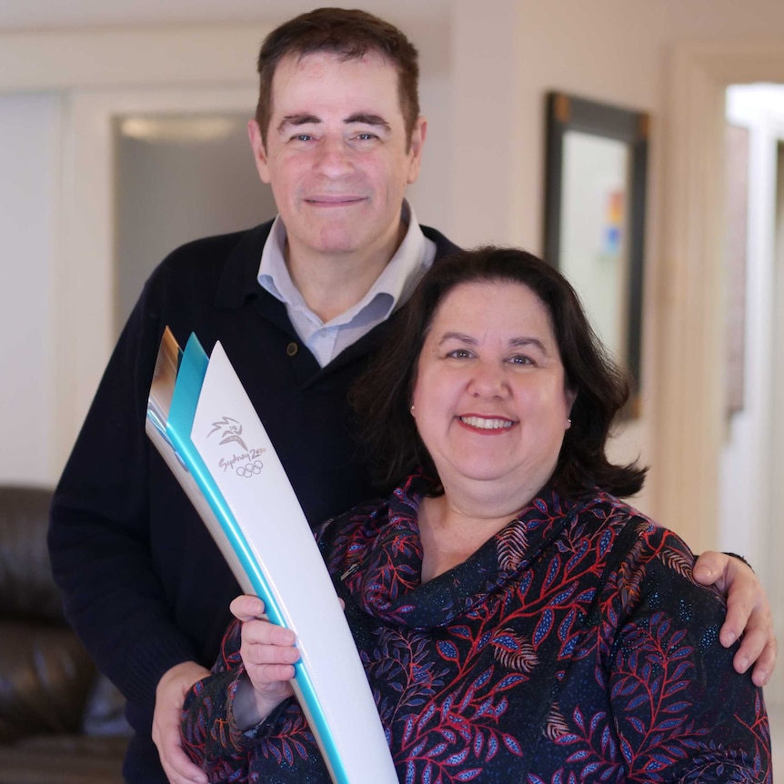 Tamara Leizer stands with her husband Tully holding the torch from the Sydney 2000 Olympics.