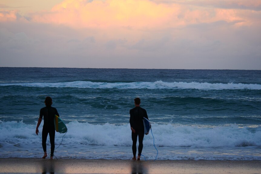 two people at beach with surfboards