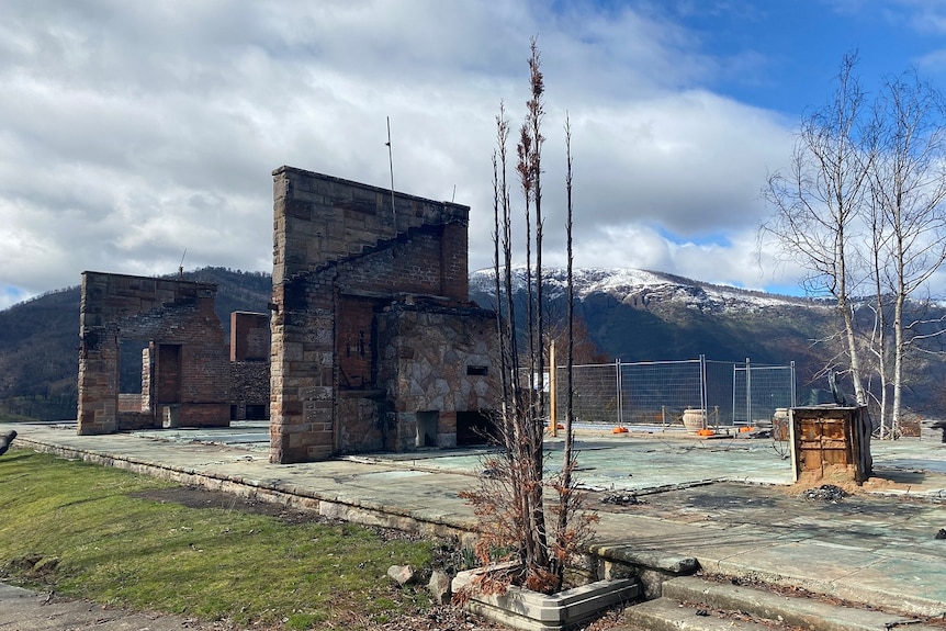 An almost bare concrete slab with signs of charring sits in front of a snow-capped mountain.