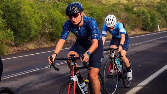 A female cyclist rides in a bunch during a road race.