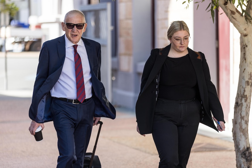 Two lawyers, a man and a woman, walking into courthouse for a trial.  