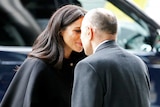 Meghan Markle rubs noses with a man wearing a suit