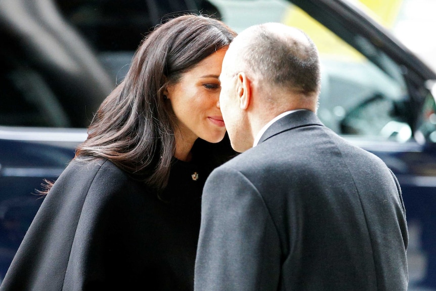 Meghan Markle rubs noses with a man wearing a suit