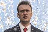 Alexei Navalny walks on the street, through the snow, and others walk beside him.
