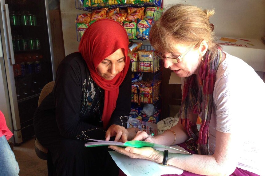 A teacher points out the page of a textbook to an adult learner in Lebanon