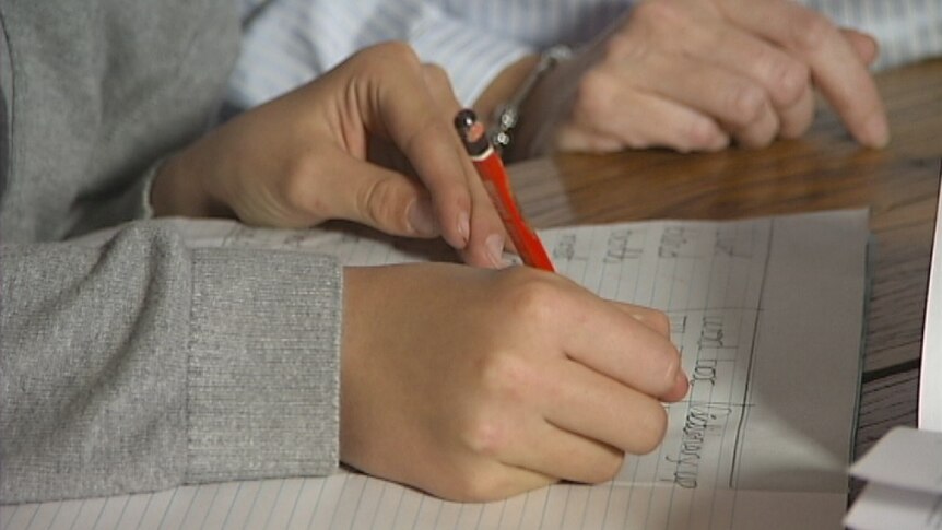 Video still: Literacy generic photo of child's hand writing on notebook while parent looks on. Aug 2012.