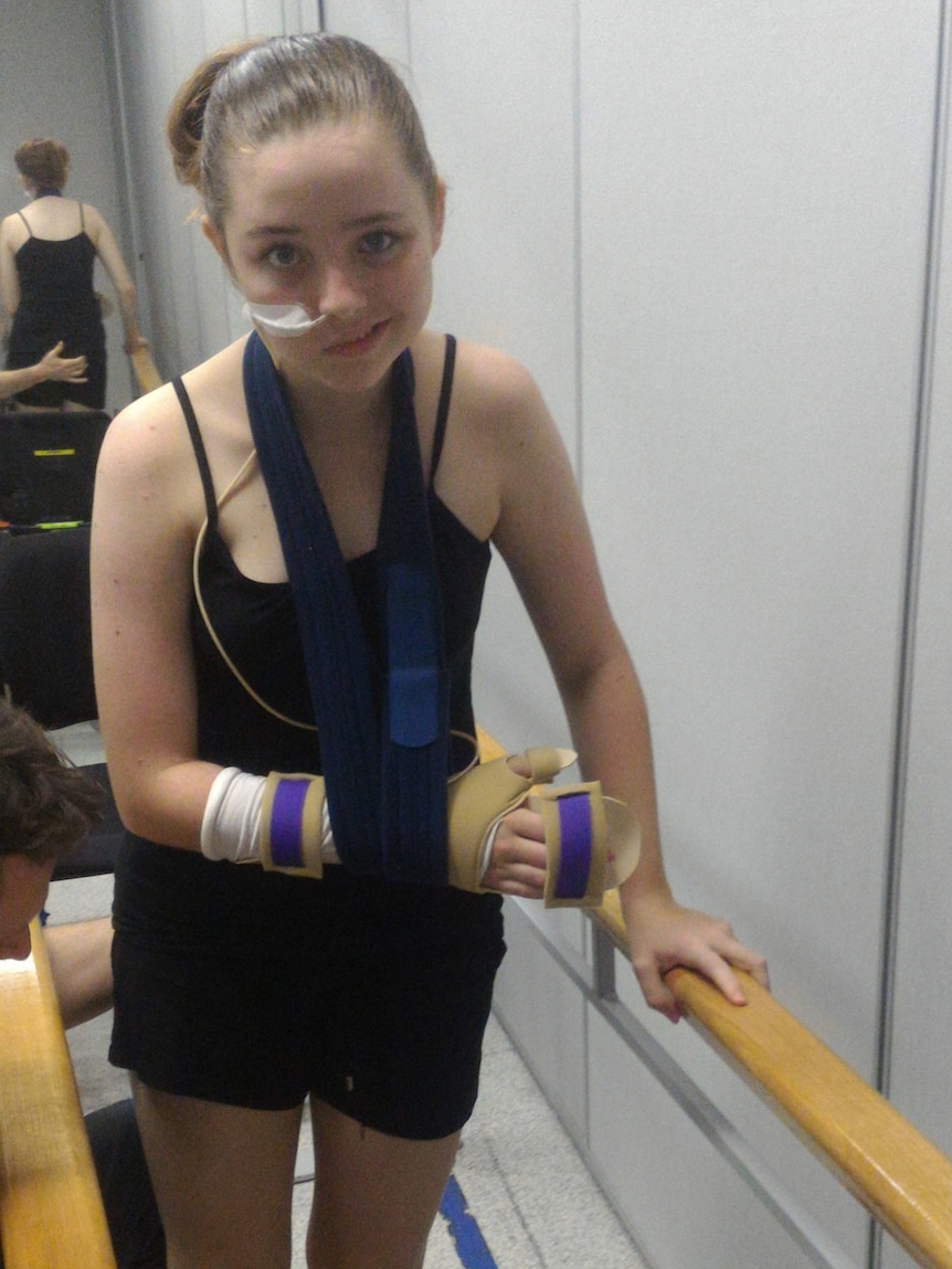 A girl with her arm in a sling holding onto two rails