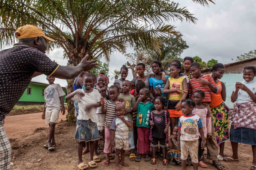 Abdul Karim Vandy, district chairman, tries to cheer up the children at VOA camp