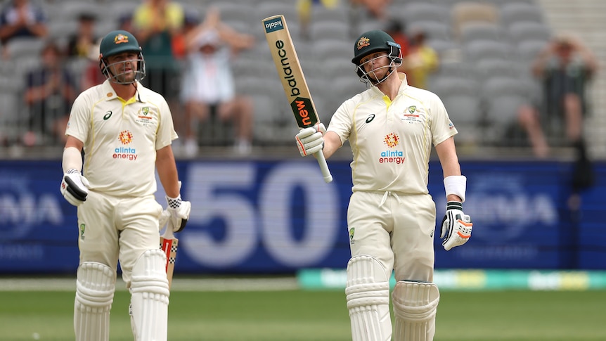 Australia batter Steve Smith holds up his bat as teammate Travis Head stands behind him during a Test against West Indies.