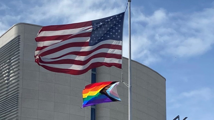 The US flag and a Pride Flag raised together.