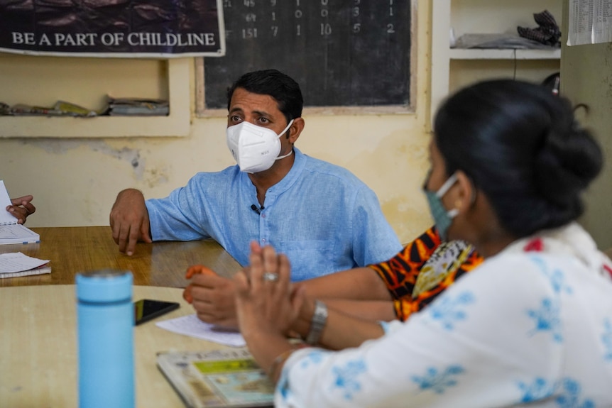 An Indian priest in a blue shirt 