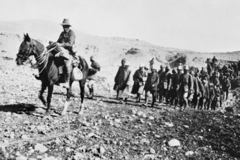 Black and white image of a large group of Turkish prisoners being led by an Australian soldier of the Light Horse on horseback.