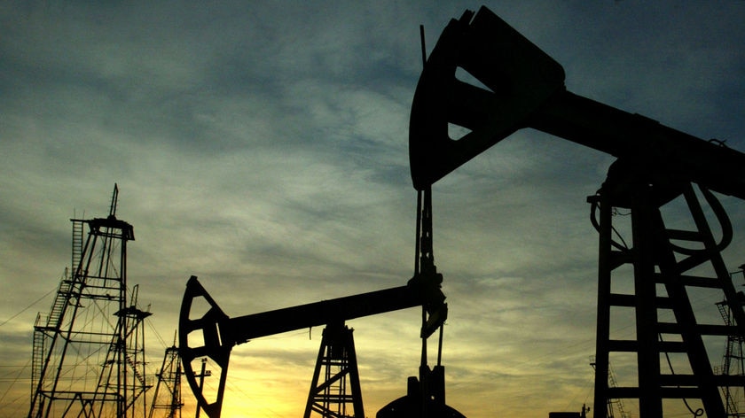 Oil derricks silhouetted against the rising sun.