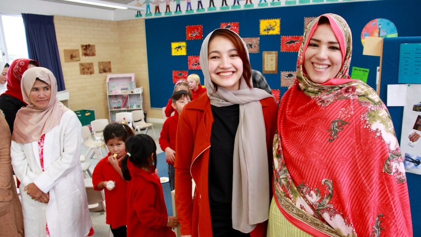 Hazara women in traditional dress in colourful room with children