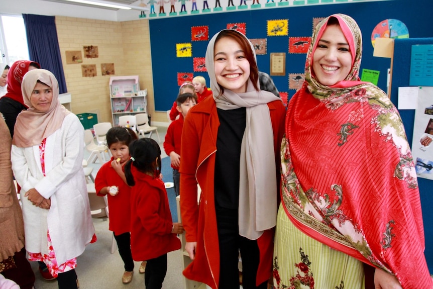 Hazara women in traditional dress in colourful room with children