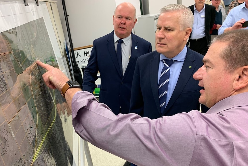 Three men look at a map.