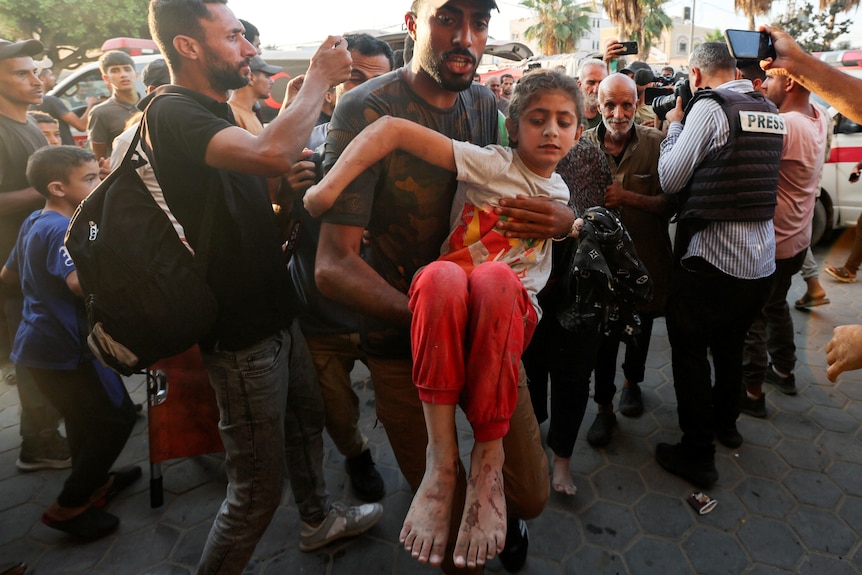 A man carries a Palestinian child.