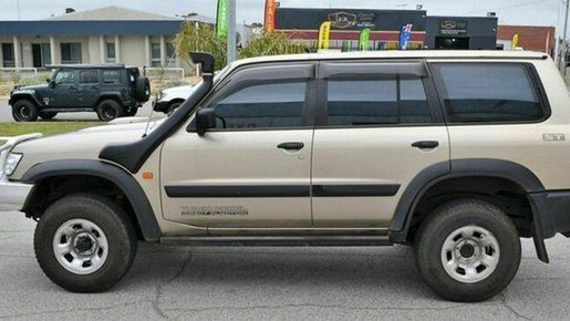 A gold-coloured four-wheel-drive vehicle parked on a road.