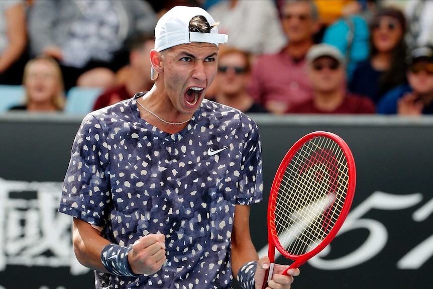 A male tennis player screams out as he pumps both his fists to celebrate winning a point at the Australian Open.