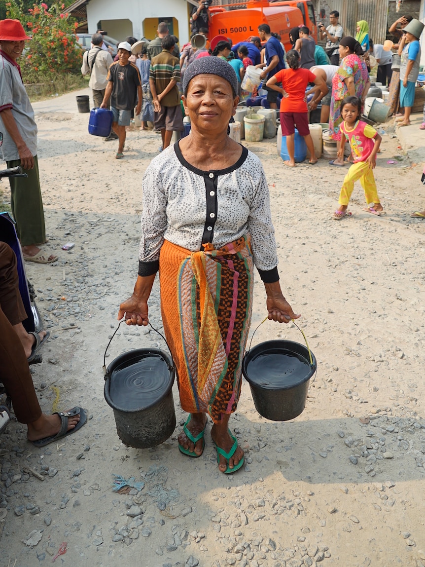 A woman carries two buckets of fresh water