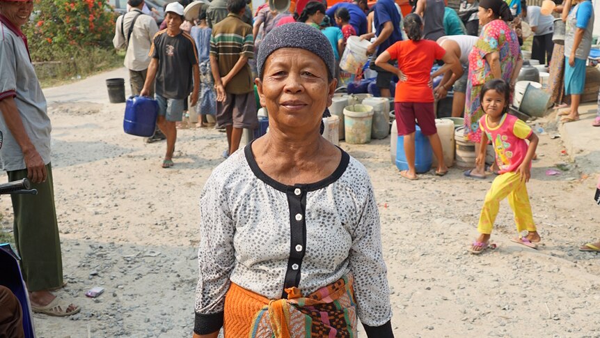 A woman carries two buckets of fresh water