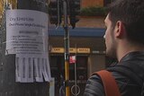 A man looks at an advertisement for a room for rent in Sydney