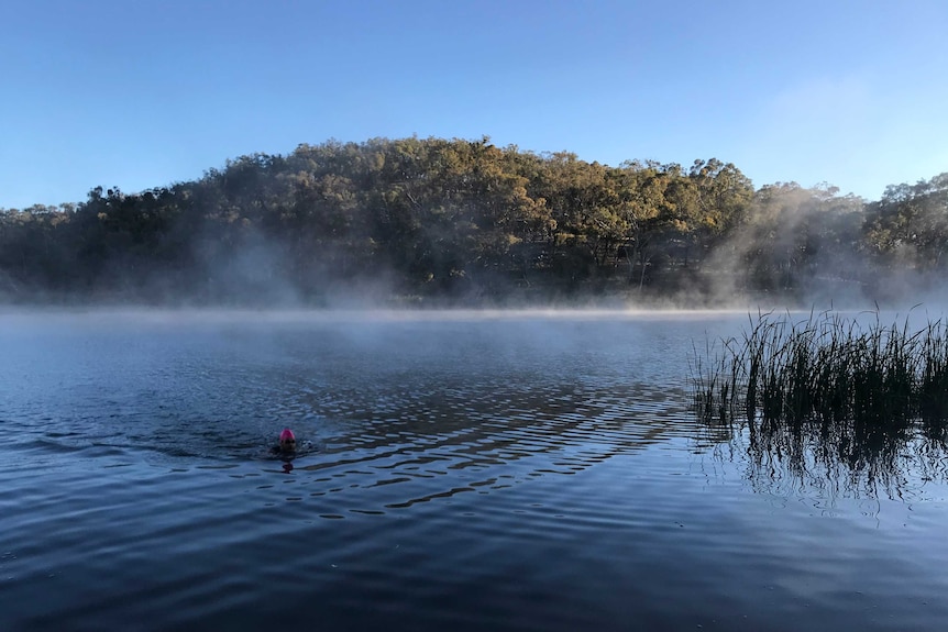 water with mist and person swimming in foreground