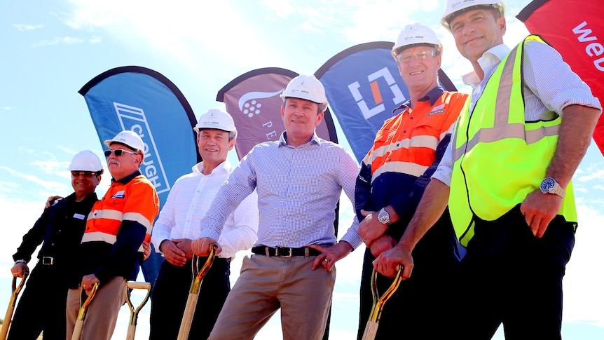 Six men in hard hats with shovels at a sod turning.